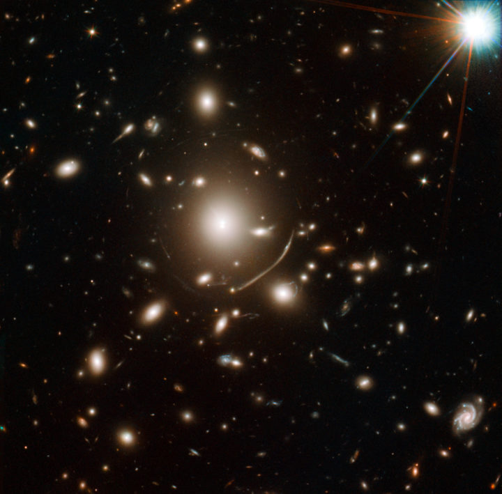 Galaksijoukko Abell S1063 kaareuttaa avaruutta niin voimakkaasti, että sen takaa olevista galakseista tuleva valo taipuu sen ympärillä ja niiden kuvat näkyvät kaarina ja kirkastumina galaksijoukon ympärillä yleisen suhteellisuusteorian ennustamalla tavalla. Kaareutumisen voimakkuus riippuu galaksien ja niitä ympäröivän pimeän aineen massasta ja siitä, miten se on jakautunut. Kuva NASA, ESA, and J. Lotz (STScI)