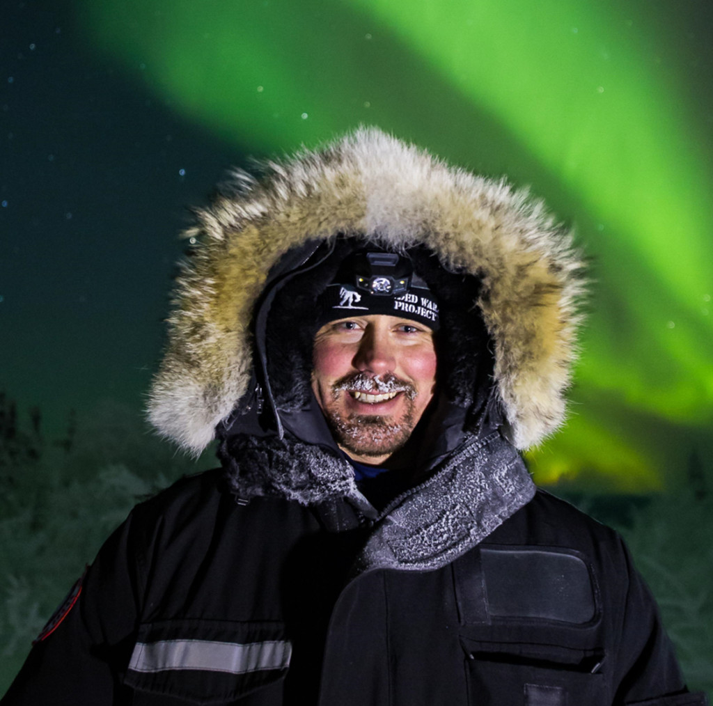 Kokenut revontulikuvaaja Ronnin Murray. Fokus on etualalla ja havaitsija valaistaan erillisellä valonlähteellä. 